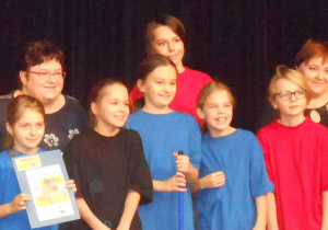 Uczniowie grupy teatralnej Siódemka ybrani w kolorowe stroje wraz z diema opiekunkami odbierają I nagrodę w przeglądzie Tomaszowskie Teatralia.